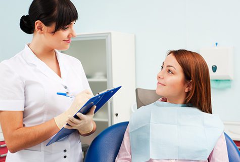 A dental assistant is getting the patient information